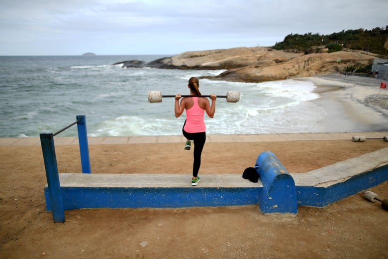 A woman lifts weights as she exercises at an outdoor improvised gym close to Ipanema beach in Rio de Janeiro on August 3, 2016.